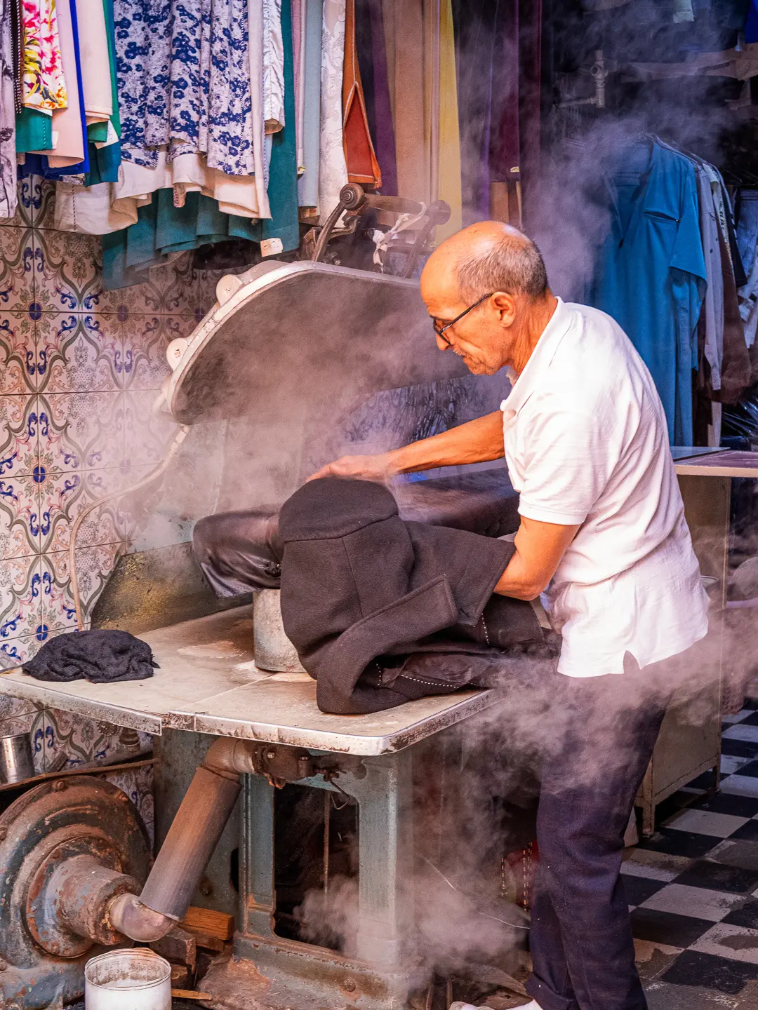 Travailleur marocain dans un pressing traditionnel parmi la vapeur Moroccan worker in a traditional steam-filled laundry