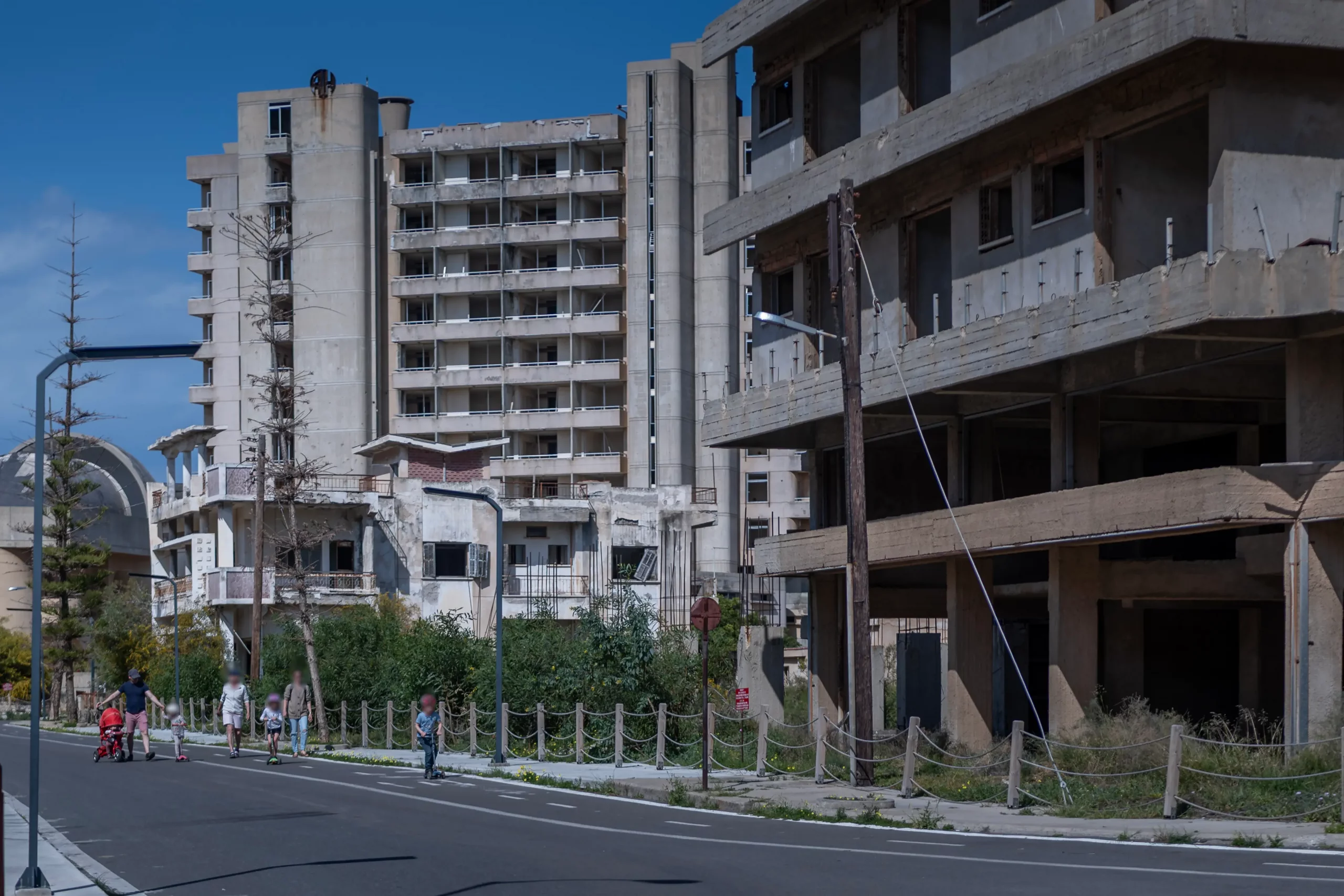 Varosha Chypre - romeneurs et familles dans une rue de Varosha, quartier balnéaire de Famagouste partiellement rouvert en 2020, devant des hôtels abandonnés depuis 1974.